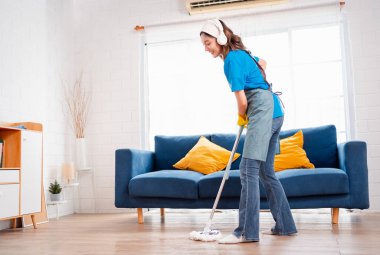 Happy Housework ya da ev hizmetçisi kadın şarkı söyleyip tozları temizliyor, küçük işletmeleri temizliyor. profesyonel ekipman eski evi temizliyor.