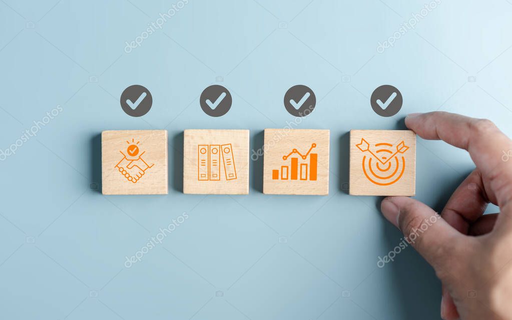 Hand holding wooden block with Quality Assurance or QA and Quality Control or QC and improvement. Standardization, certification. Compliance to regulations service and standards.