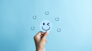 Mavi gülen surat tutan eller. Zihinsel sağlık olumlu düşünce ve büyüme zihniyeti, ruh sağlığı mutluluğa iyileşme duygusu.