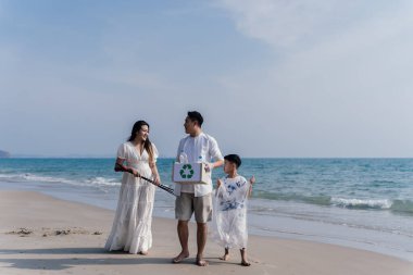 Mutlu gönüllü işçi ailesi sahilde çöp torbalarıyla plastik şişe temizliyor..