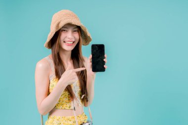 Online bilet rezervasyonu ve alımı için akıllı telefonu kullanan Asyalı Kadın, stüdyonun arka planında cep telefonu tutan genç kadın yaz tatili kavramı.