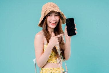 Online bilet rezervasyonu ve alımı için akıllı telefonu kullanan Asyalı Kadın, stüdyonun arka planında cep telefonu tutan genç kadın yaz tatili kavramı.