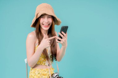 Online bilet rezervasyonu ve alımı için akıllı telefonu kullanan Asyalı Kadın, stüdyonun arka planında cep telefonu tutan genç kadın yaz tatili kavramı.