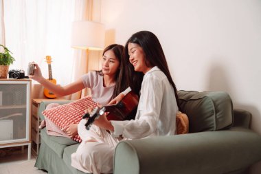 Asya Kadın Müzik Gitarı Birlikte Çalıyor Salonda Genç Gençler Oturma Odası, Arkadaşların Neşeli Toplantısı Müzik Paylaşımı, Gülüşmeler ve Evde Gitar Çalarak Rahatlama