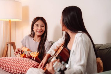 Asya Kadın Müzik Gitarı Birlikte Çalıyor Salonda Genç Gençler Oturma Odası, Arkadaşların Neşeli Toplantısı Müzik Paylaşımı, Gülüşmeler ve Evde Gitar Çalarak Rahatlama