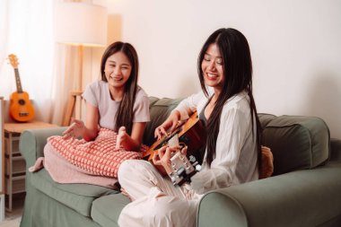 Asya Kadın Müzik Gitarı Birlikte Çalıyor Salonda Genç Gençler Oturma Odası, Arkadaşların Neşeli Toplantısı Müzik Paylaşımı, Gülüşmeler ve Evde Gitar Çalarak Rahatlama