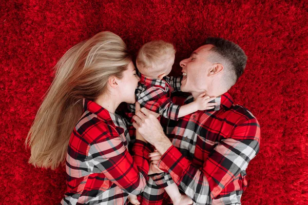 Happy Young Parents Baby Boy Same Pyjamas Lying Red Floor — Stock fotografie