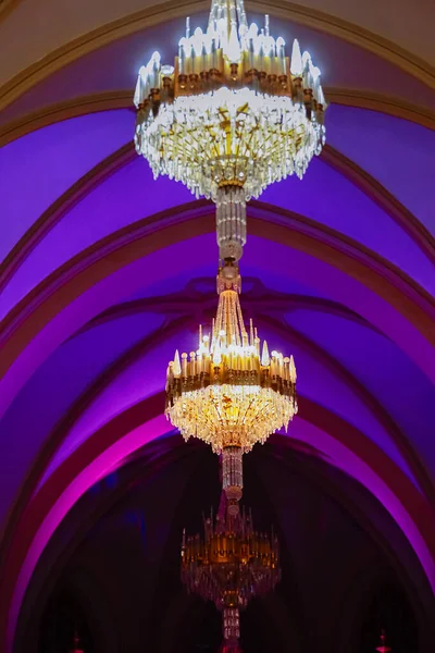 Stock image Elegant luxury crystal chandeliers on ceiling in purple and blue light. Emphasis on luxury, used in various places such as palace church, residence.Decorative elegant vintage and Contemporary Concept