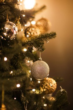 Güzel köknar dallarının parlak altın mücevheri ya da topu, kostüm süsleri ve ışıkları, Noel tatilleri arka planında yakın görünümü. kopyalama alanı. Noel ağacının süslemesi. Yeni Yıl Kutlaması 2023.