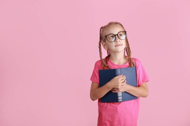 Komik örgülü gözlüklü sevimli küçük kız kitabı tutuyor, gülümsemek pembe arka planda düşünmektir. Okula dönelim. Çocuk eğitimi ve öğrenimi. Okul çocuğu bilgi topluyor.