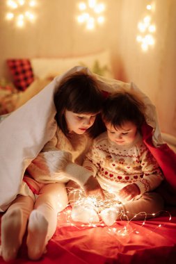 Solucan kıyafetleri içinde iki küçük kız eğleniyor, iletişim kuruyor ve sırlarını battaniyenin altında, yatak odasındaki süslü çelenklerin altında paylaşıyorlar. Yeni yıl aile tatili..