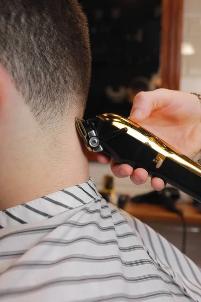 理发师 理发师 用一把金色的电动剪子 剃须刀 从客户的后脑勺剪头发 理发店的男人去拜访理发店的理发师 理发师正在修剪顾客的头发 美容院 — 图库照片