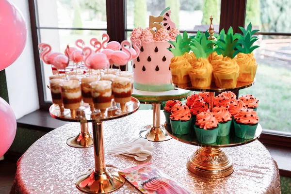 birthday exitic catering, table with modern desserts, cupcakes, sweets with flamingo. delicious candy bar at expensive birthday party. space for text. baby shower. holiday celebration.