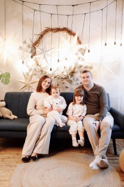 Babam, annem ve iki güzel kızımla birlikte Noel ve yeni yılı kutlamak için dekore edilmiş oturma odasındaki kanepede dinlenirken sevgi dolu bir aile. Kameraya bakıyorum. Evde sıcak bir kış akşamı..