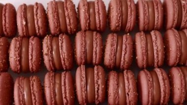 Brown sweet french macaron cakes with chocolate topping in row on the cafe display. Sets of desserts from almond dough and italy merenga in the pastry. Macaroon dessert In bakery shop