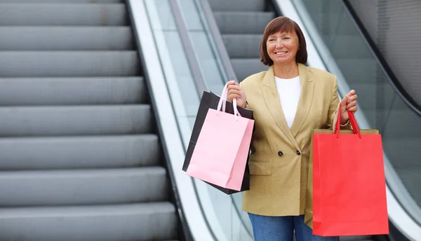 Zarif Gülümseyen Yetişkin Kadın Renkli Alışveriş Torbalarıyla Yürüyen Merdiveni Kaldırıyor — Stok fotoğraf