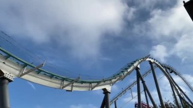 TARRAA, SPAIN-OCTOBER, 2022: eğlence parkı Port Aventura Dünyası 'ndaki Shambala cazibesi - bir grup heyecanlı insan mavi gökyüzü arka planında lunapark trenine atlıyor. Avrupa 'nın en büyük lunapark treni.