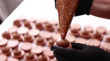 Şefin ellerinin çikolatalı badem kabuğuna fındıklı tuzlu karamelli ganache kreması koyması. Makarna Fırını Konsepti. Pişirme, Yemek ve Pişirme Konsepti. Şekerleme ve Pişirme Konsepti