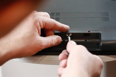 Tamircinin elleri dizüstü bilgisayardaki vidaları tornavidayla söküyor. Bilgisayar servisi ve onarım. Onarım atölyesinde dizüstü bilgisayar parçalanıyor. Elektronik geliştirme, elektronik cihaz onarımı