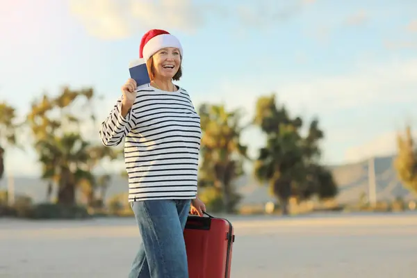 Γελώντας Σάντα Ενήλικη Γυναίκα Χριστουγεννιάτικο Καπέλο Κρατώντας Κόκκινη Βαλίτσα Διαβατήριο — Φωτογραφία Αρχείου