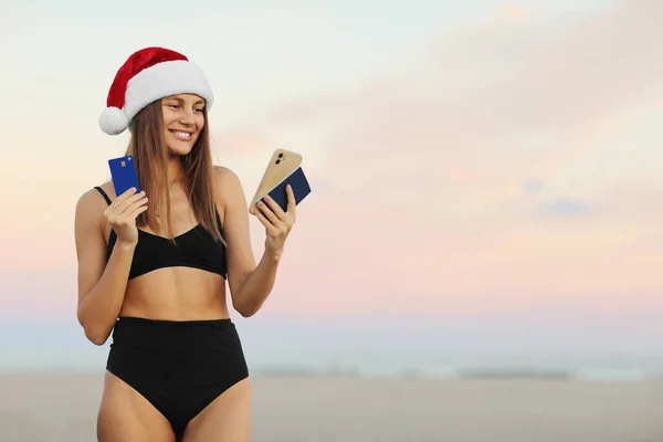 Szczęśliwa Młoda Kobieta Kapeluszu Santa Strój Kąpielowy Smartfonem Kartą Kredytową — Zdjęcie stockowe