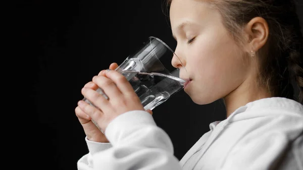 水平衡和儿童保健 小女孩在家里喝新鲜而透明的纯过滤矿泉水 为了健康起见 口渴的脱水少年每天早晨都要喝玻璃杯水来解渴 — 图库照片