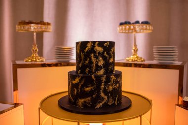 Lüks çikolatalar. Parti, doğum günü, sevgililer günü, düğün için masanın üzerinde süslü iki katlı çikolata süslemesi. Arka planda lezzetli tatlı çeşitleri ve tabaklar var..