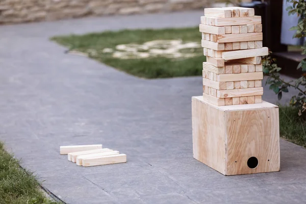 Jenga, multistory tower of wooden blocks. Group game of physical skill with big blocks for outdoors, vertical. Game for children and adult persons.
