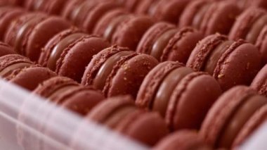 Brown sweet french macaron cakes with chocolate topping in row on the cafe display. Sets of desserts from almond dough and italy merenga in the pastry. Macaroon dessert In bakery shop