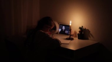 Öğretmen Ukrayna 'da bilinç kaybının, evde ışık olmadan, mum ışığında, sanal sınıfta dijital tablet üzerine video konferans konuşmasıyla ders çalışarak öğrenildiğini açıkladı..