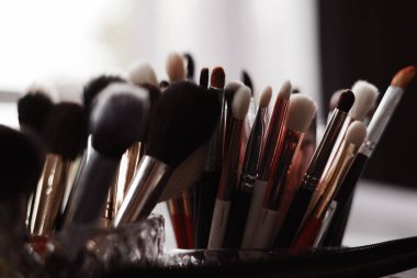 Güzellik salonundaki cam bardaklarda profesyonel makyaj fırçaları. Doğal ve sentetik kıllar, makyaj aletleri. Güzellik blogu için mükemmel. Farklı boyutlarda ve şekillerde fırçalar..