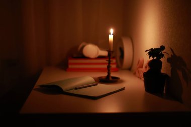 Karanlık odada şamdanla mum yakmak çalışma masasında kağıt defterin kalemle aydınlatıldığı yerde. Bilinç kaybında evde çalışmak ve çalışmak. Elektrik sorunu.