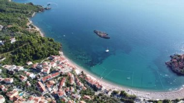 Karadağ 'ın turkuaz Adriyatik kıyı şeridine ait hava manzarası, güzel bir yaz gününde, insansız hava aracından. Sveti Stefan adasının yukarısı panoramik. Turizm ve eğlence konsepti. Aero Videografi.