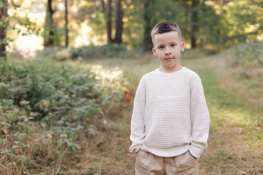 Küçük çocuğun portresi gülümsüyor ve arka plandaki kameraya bakıyor. Çocuk, ebeveynlik, mutlu ve neşeli duygular, kaygısız, komik surat, yeni bir dünya keşfet. Mutlu bir çocukluk kavramı.
