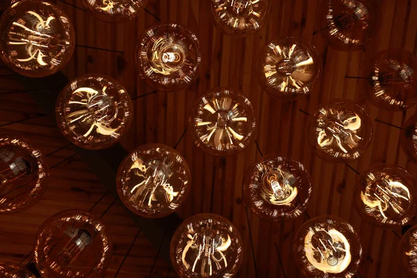 Stylish, modern and decorative lamps of Edison of round shape in the rows. Light bulbs in retro style. A lot celling glowing vintage LED lamps. Object for interior decoration, selective focus photo.