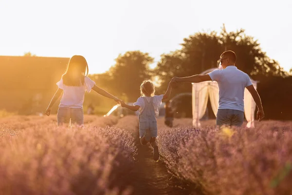 happy family day. young father, mother and child daughter are having fun together in the lavender field and looking at each other. happy couple with kid enjoy summer holiday vacation. family look.