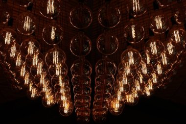 Stylish, modern and decorative lamps of Edison of round shape in the rows. Light bulbs in retro style. A lot celling glowing vintage LED lamps. Object for interior decoration, selective focus photo.