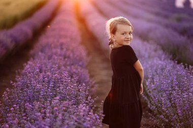 Elinde bir demet lavanta çiçeğiyle sevimli bir kızın portresi. Bir çocuk gün batımında lavanta tarlasında yürüyor. Siyah elbiseli çocuk yaz tatilinde doğada eğleniyor.