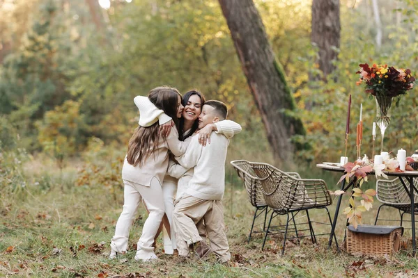 Mothers day. Happy young mother with teen daughter and little son are having fun and hugging outdoors in the autumn park. Family day. Idyllic stylish family having picnic on holiday. happy childhood