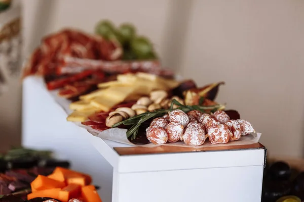 Appetizers table with meat and cheese. Salami, sausages, variation of cheese, grapes, tomatoes, green olives, rosemary, tapas on wooden plates. Snack finger food meal for wine, starter