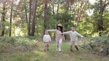 Three happy childs are having rest and having fun in park in fresh air. Children outdoor activity in warm day. Sibling, girl and two boys are running on green grass in the forest. Kid dream team