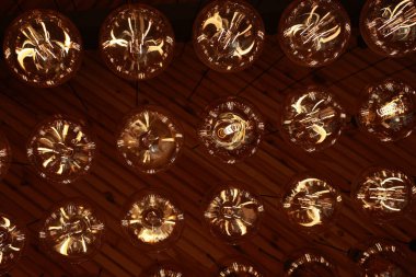 Stylish, modern and decorative lamps of Edison of round shape in the rows. Light bulbs in retro style. A lot celling glowing vintage LED lamps. Object for interior decoration, selective focus photo.