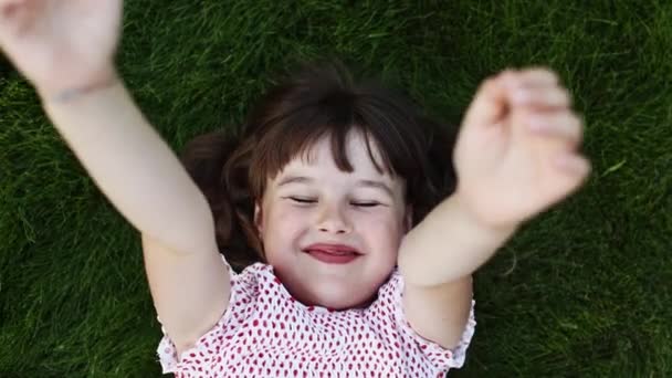 Międzynarodowy Dzień Dziecka Szczęśliwa Dziewczynka Leżąca Zielonej Trawie Patrząca Wyciągająca — Wideo stockowe