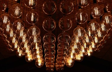 Stylish, modern and decorative lamps of Edison of round shape in the rows. Light bulbs in retro style. A lot celling glowing vintage LED lamps. Object for interior decoration, selective focus photo.