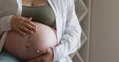 Young expectant mother stroking, caressing her big naked belly enjoy maternity resting at home, cropped shot of unknown pregnant woman. Happy motherhood, true love concept. Mother and baby connection.