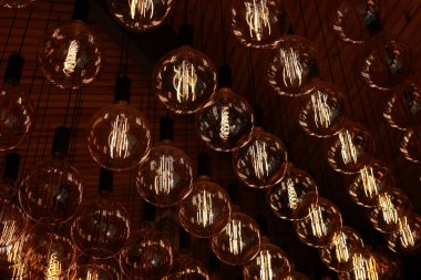Stylish, modern and decorative lamps of Edison of round shape in the rows. Light bulbs in retro style. A lot celling glowing vintage LED lamps. Object for interior decoration, selective focus photo.