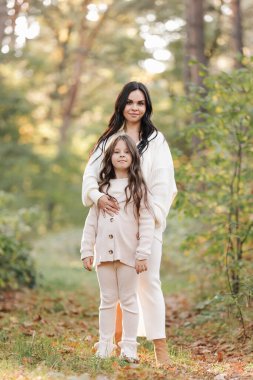 Mothers day. Beautiful smiling young mom with teen daughter are hugging and looking at camera outdoors in the autumn park. Family day. Idyllic stylish family of two communicate alone. happy childhood