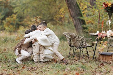Mothers day. Happy young mother with teen daughter and little son are having fun and hugging outdoors in the autumn park. Family day. Idyllic stylish family having picnic on holiday. happy childhood