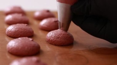 Profesyonel aşçı makaron tatlısı hazırlıyor. Kurabiye pişirmek için tepsideki boru torbasından kas kreması çıkartılan yakın plan. Pişirme, pişirme kavramı. Kapat..