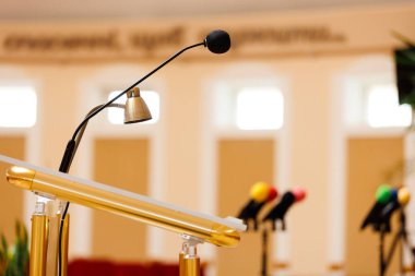 Podyumdaki diğer renkli mikrofonların arka planda bulanık olduğu bir mikrofonun seçici odağı. İletişim, medya, basın toplantısı, etkinlik, performans, politika, şirket kavramı